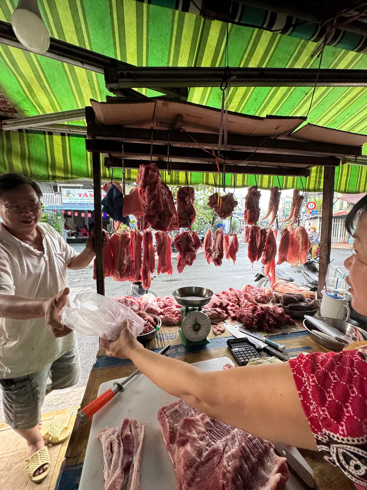 Chủ tiệm gói thịt đưa cho khách mua