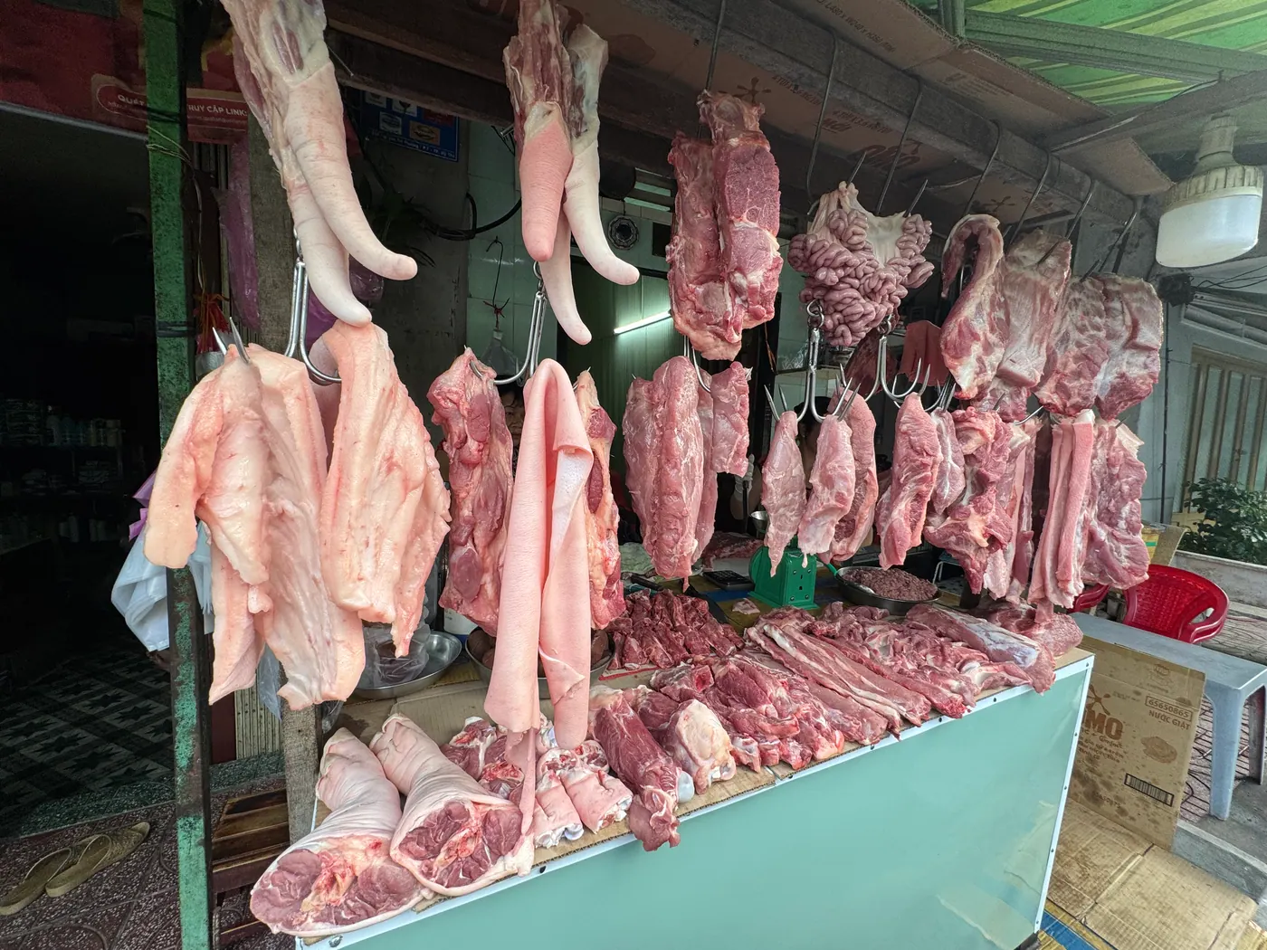 Thịt heo tươi treo trên móc tại sạp Bé Sáu